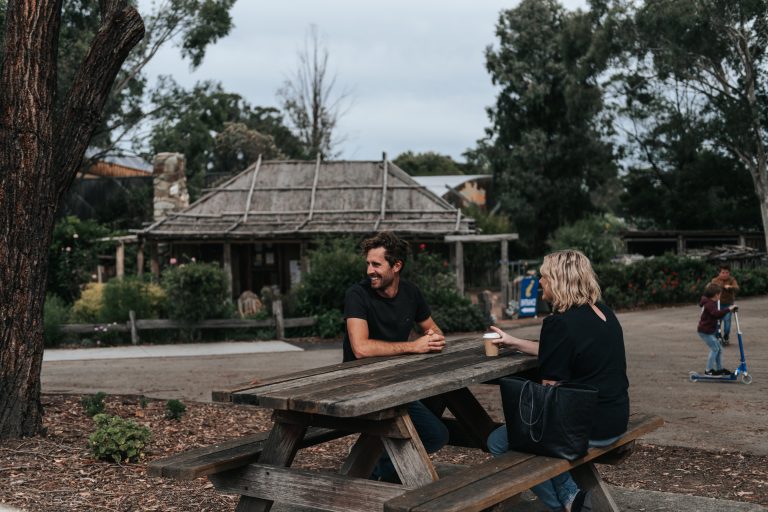 zxdgl-orbost-couple-sitting-at-picnic-table-in-front-of-rustic-shed-768x512.jpeg